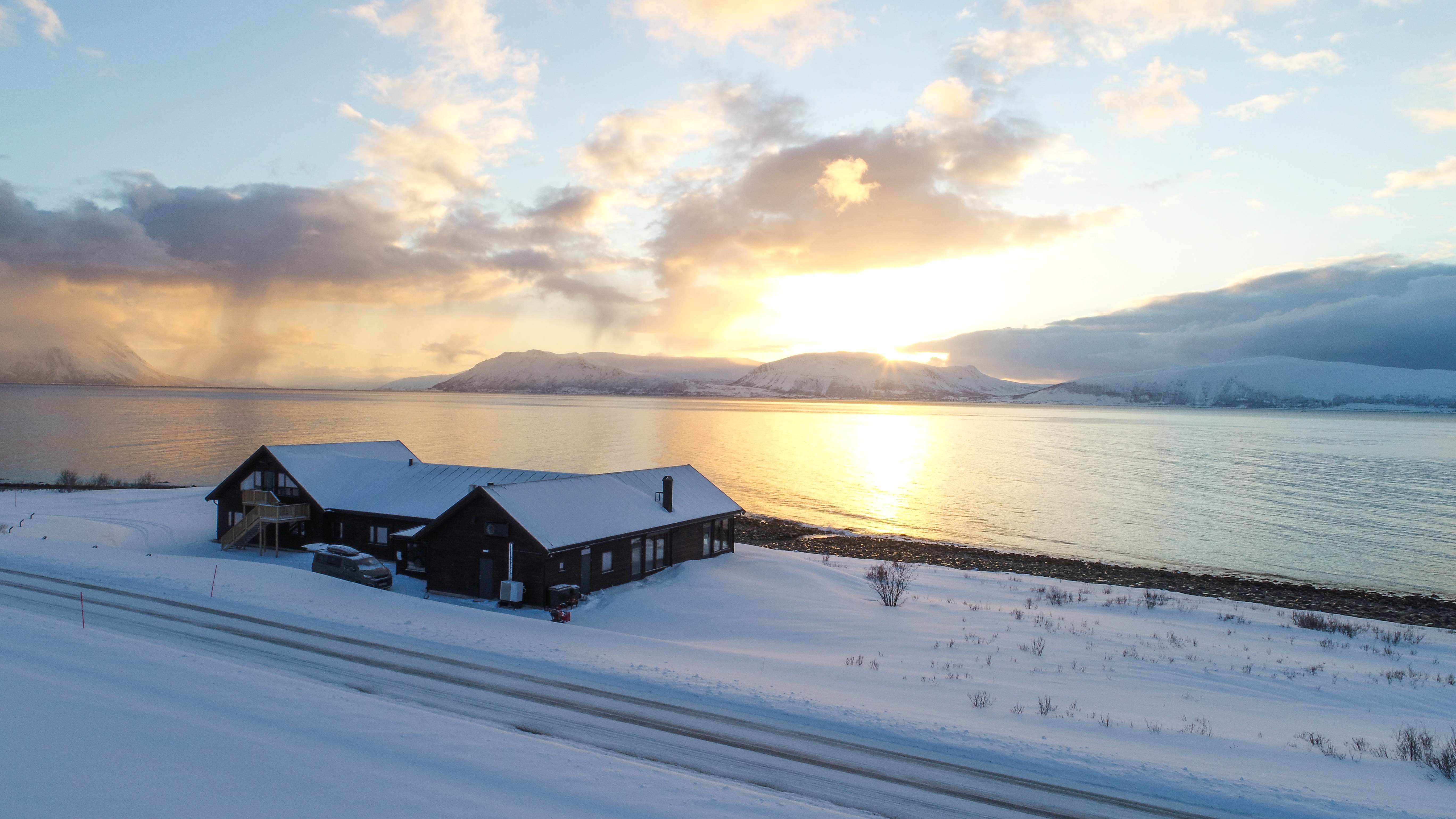 View of the Lyngen Experience Lodge over the water at sundown, Norway